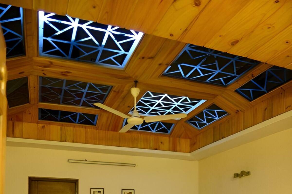 Une chambre à coucher comprenant un lit, un bureau et un plafond agrémenté de lucarnes aux formes géométriques.