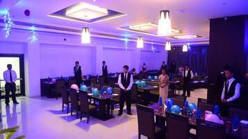A banquet hall with tables set for a formal event, featuring blue balloons and table settings.