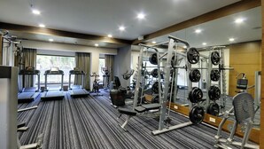 Un gimnasio con cintas de correr, máquinas de pesas y pesas libres.