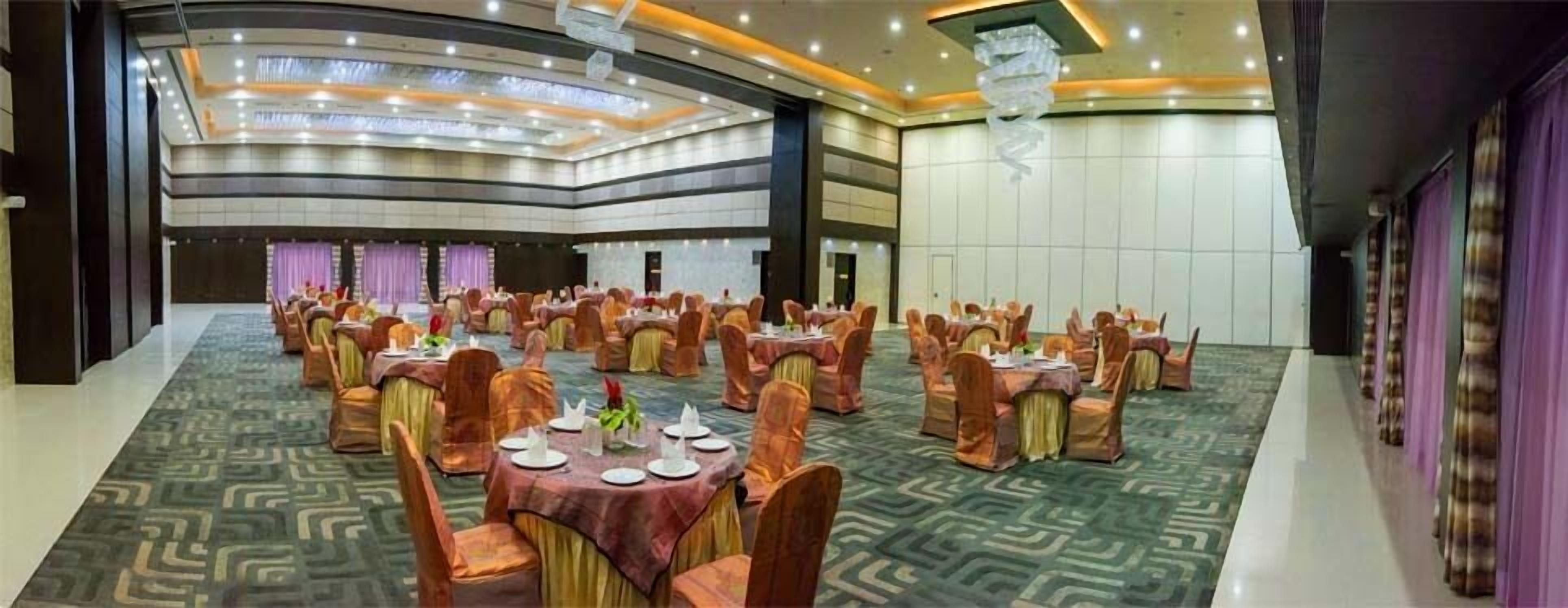 Un amplio salón de banquetes con varias mesas redondas y sillas, dispuesto en un espacio generoso.