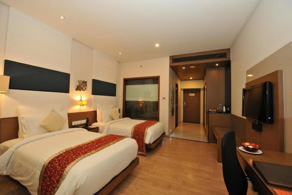 Une chambre d’hôtel avec deux lits, un bureau, une télévision et un coin repas.