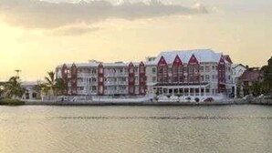 Un hotel frente al agua con varios pisos, balcones y una llamativa línea de techo roja.