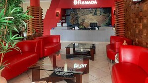 Un área de recepción con sofás rojos, una mesa de centro de vidrio y un mural en la pared.
