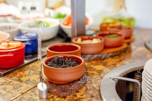 Uma mesa de buffet com diversos pratos e condimentos em pequenas tigelas.