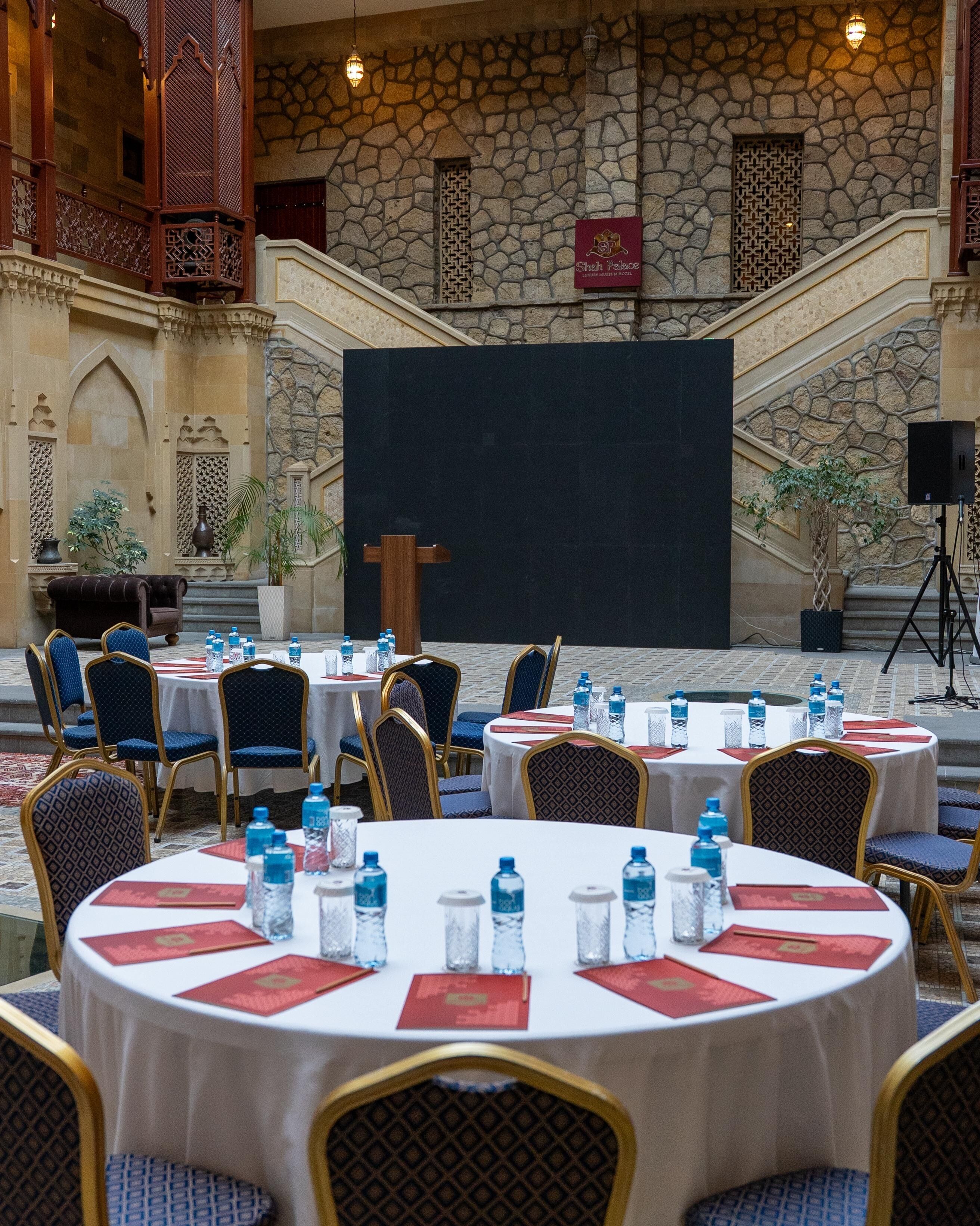 A conference room with round tables, chairs, and a large screen.