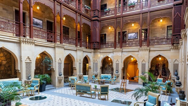 A spacious courtyard with multiple seating areas, including sofas and chairs, surrounded by arches and a high ceiling. - Shah Palace Luxury Museum Hotel (Baku)