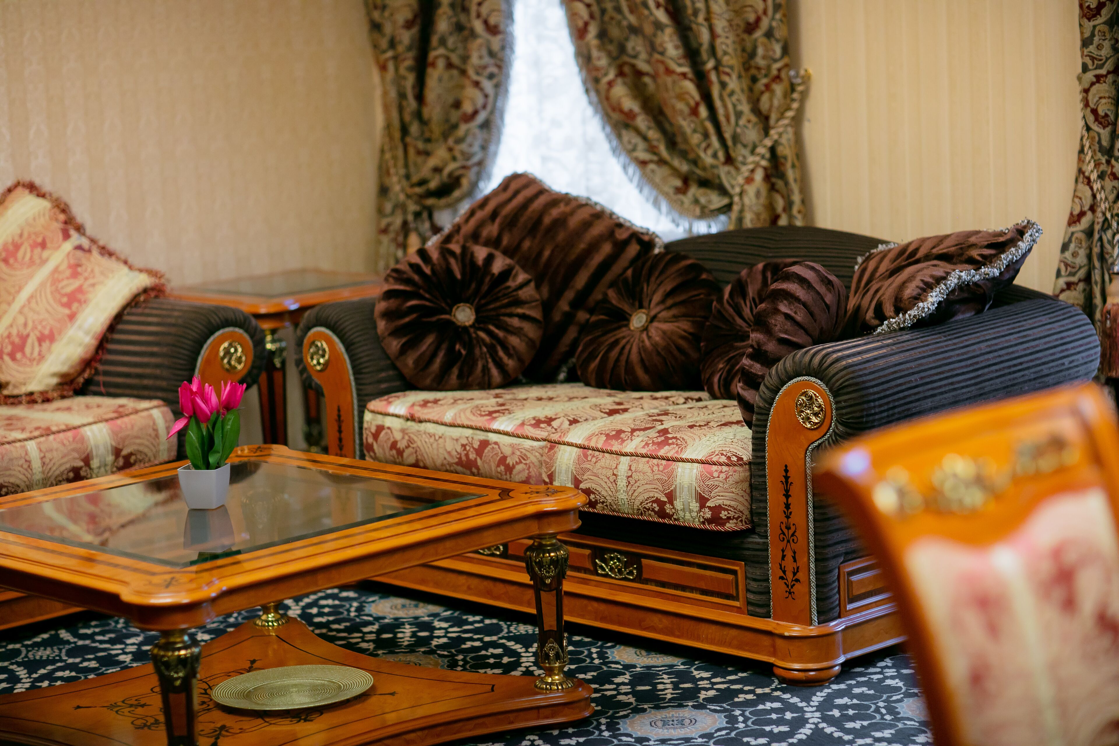 Un salón tradicional con un sofá, una mesa de centro y un jarrón decorativo con flores.
