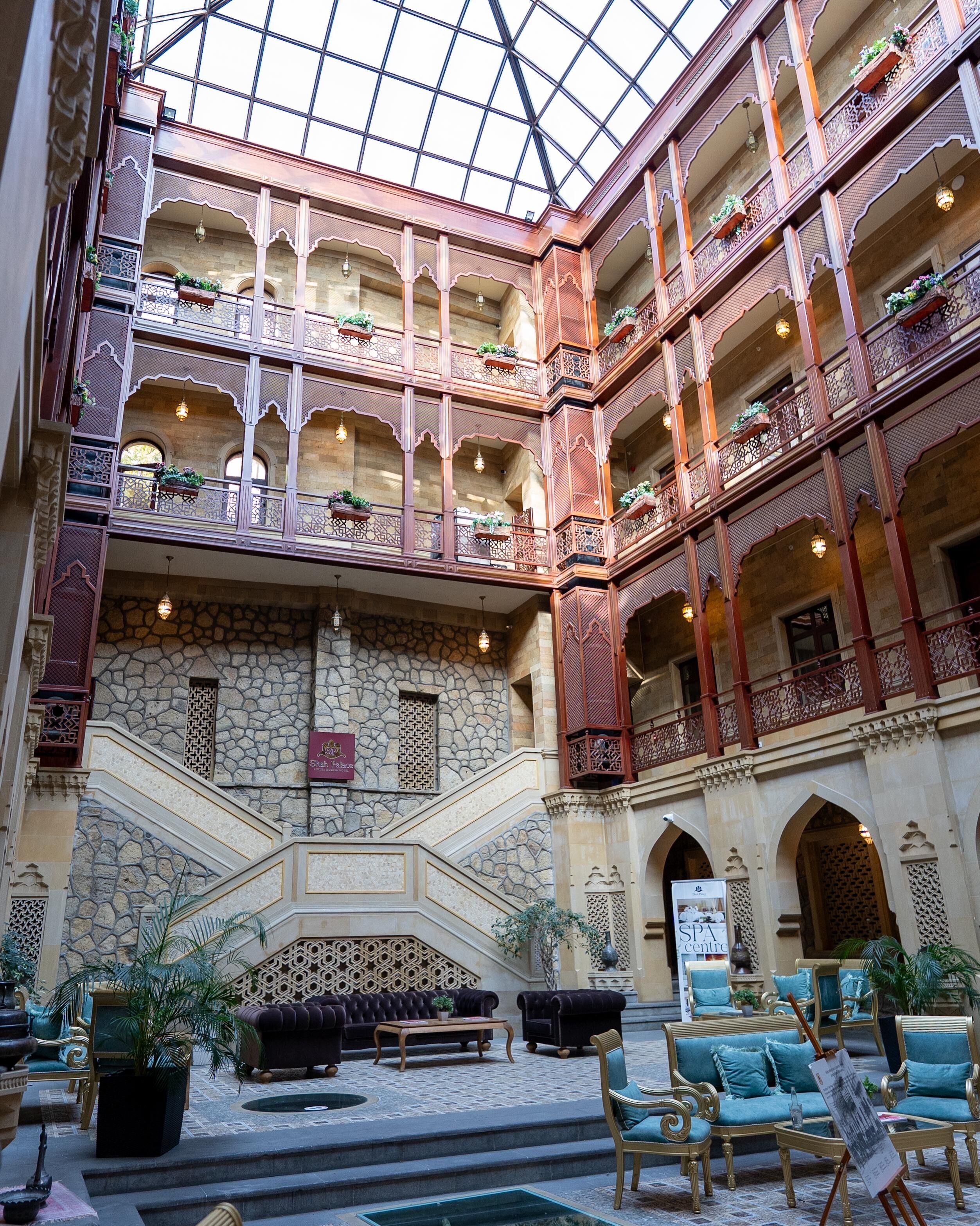 A multi-level atrium with ornate balconies, stone walls, and a central staircase.