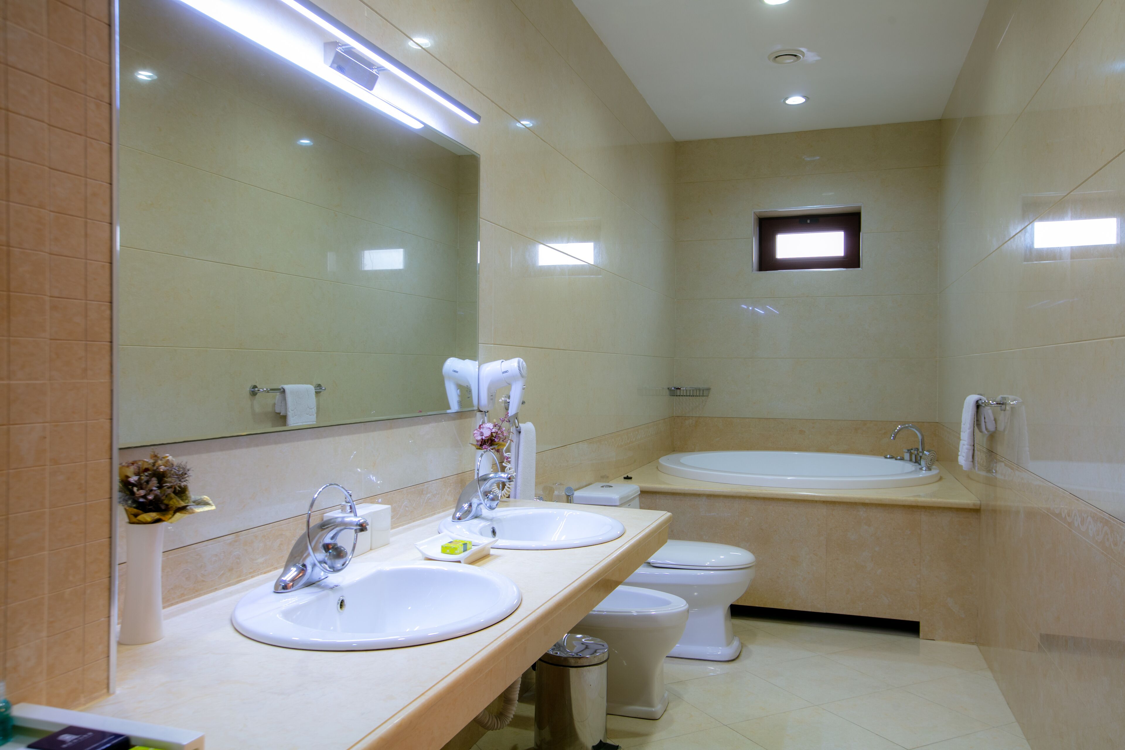 A modern bathroom with two sinks, a toilet, and a large bathtub.