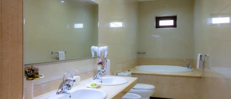 A modern bathroom with two sinks, a toilet, and a large bathtub.