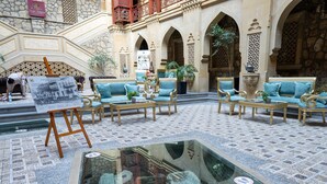 A spacious lobby with ornate architecture, a central glass table, and seating areas. - Shah Palace Luxury Museum Hotel (Baku)