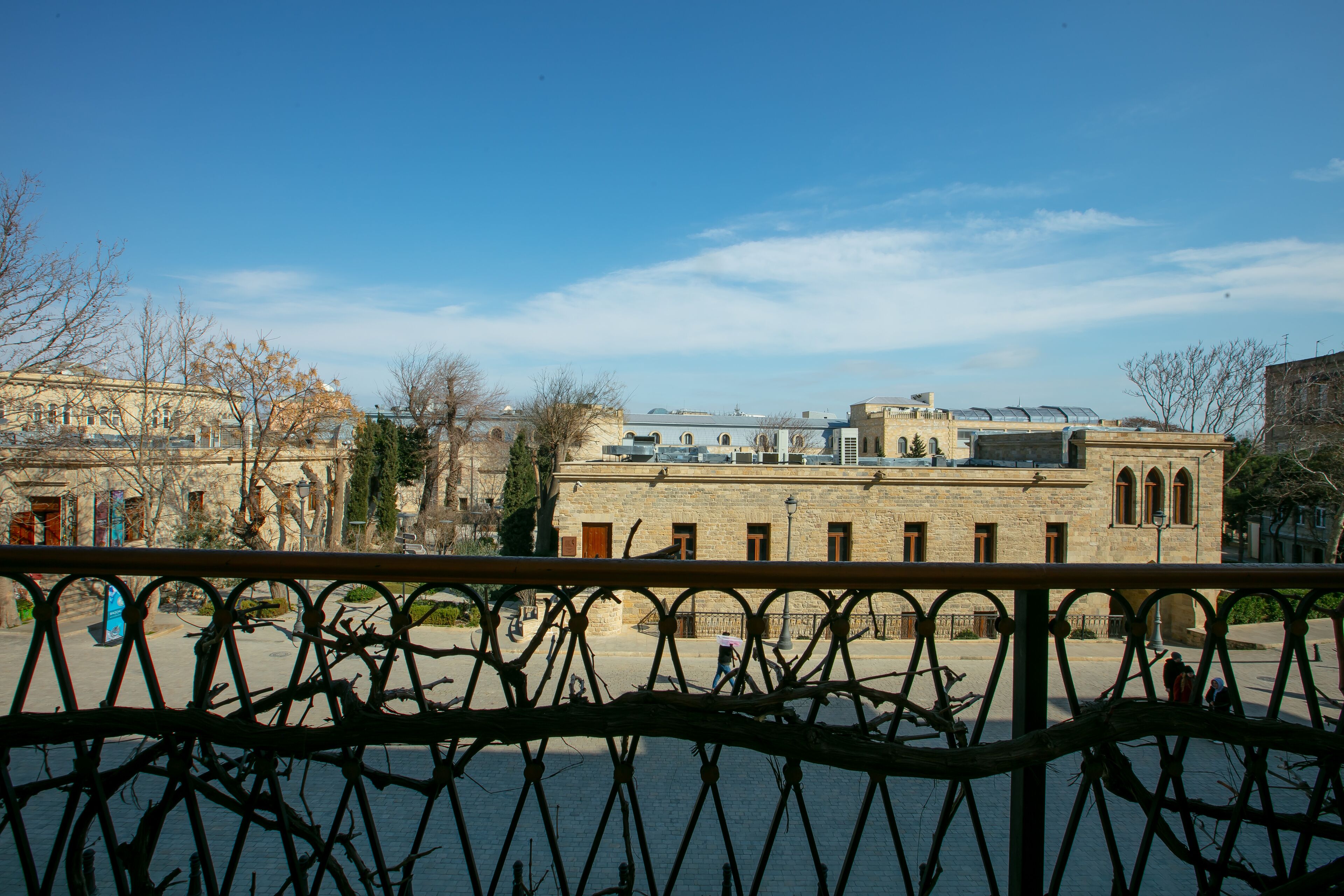 A courtyard with a building featuring arched windows and a flat roof.