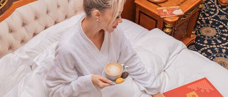 A person sitting on a bed with a book and a cup of coffee.