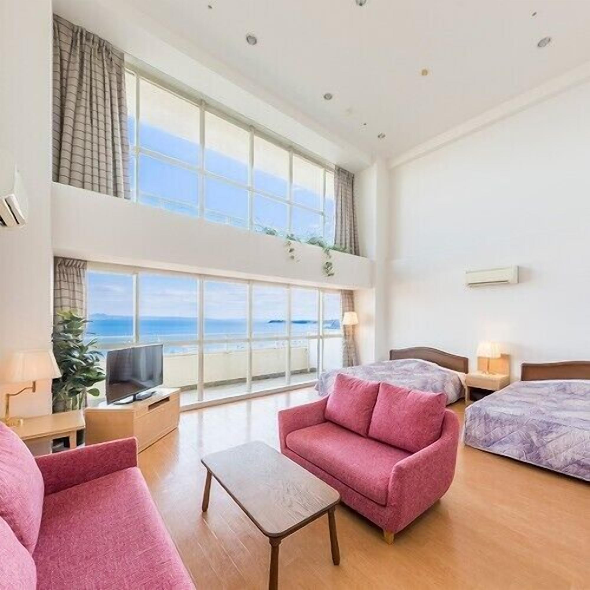Een hotelkamer met een groot raam, een televisie, een bank, een bed en een kleine tafel.