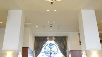 A hotel lobby with a chandelier, a staircase, and a reception desk.