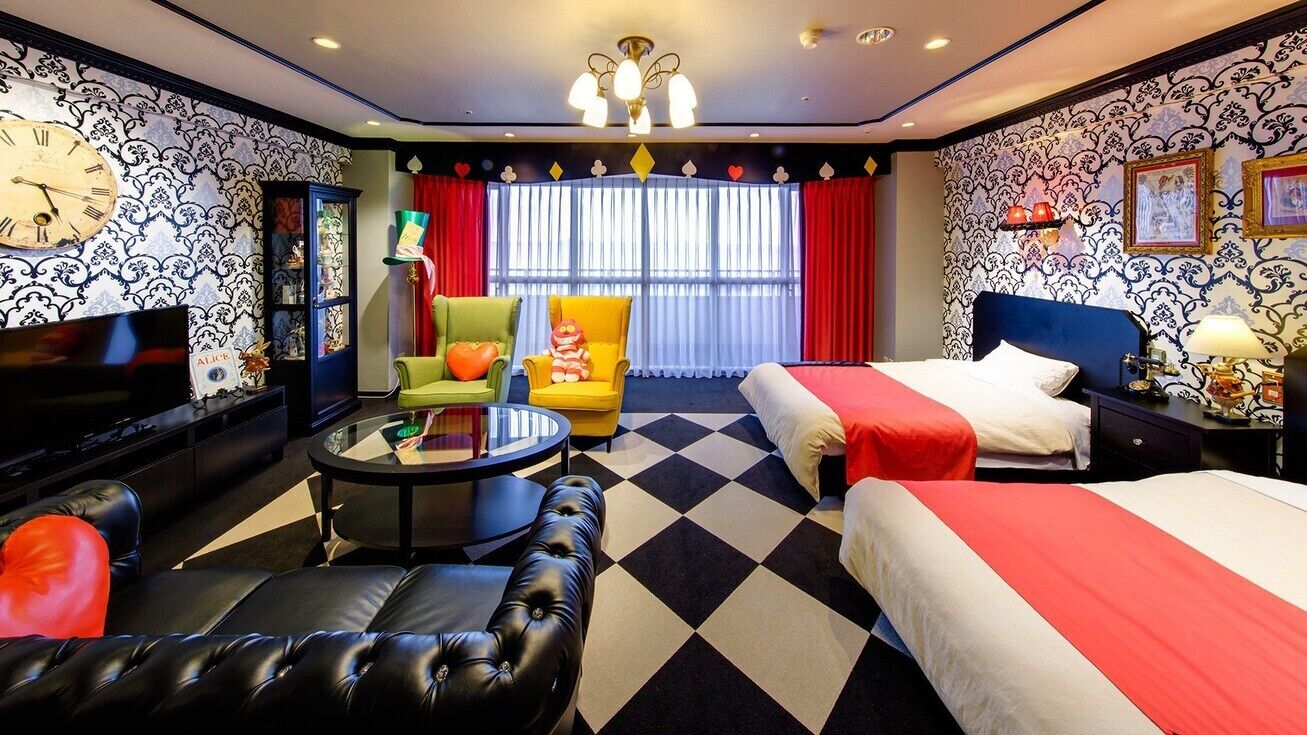 Een hotelkamer met twee bedden, een bank, een televisie, een kroonluchter en een geruit vloertje.