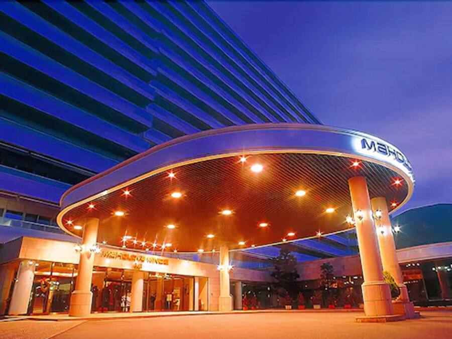 A modern hotel entrance with a circular atrium, prominent signage, and a large glass facade.