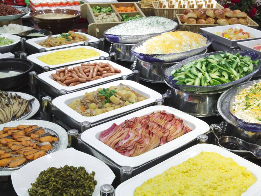 A buffet with various food items including meats, vegetables, and cheeses.