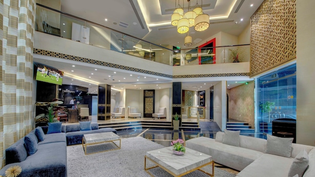 Un amplio vestíbulo con diseño moderno, que cuenta con una generosa zona de estar, una escalera y una pantalla de televisión.