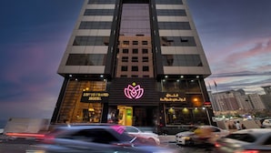 Un hotel moderno con un logotipo destacado, una entrada amplia y varios pisos.
