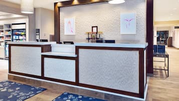 Un mostrador de recepción con una pared decorativa, una alfombra azul y un cuadro enmarcado.