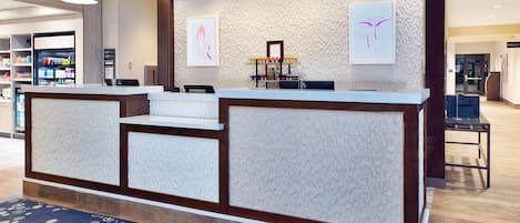 A reception desk with a patterned wall, a blue carpet, and a framed picture.