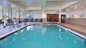 An indoor swimming pool with clear water, a diving board, and a lifeguard station. - Hilton Garden Inn Akron (Akron)