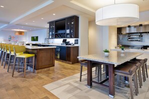 A modern kitchen with a central island, bar stools, and a dining table.