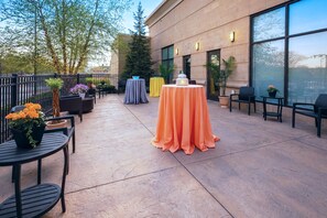 An outdoor patio area with round tables, chairs, and potted plants. - Hilton Garden Inn Akron (Akron)