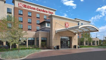 A Hilton Garden Inn with a brick facade, large windows, and a covered entrance.