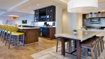 A modern kitchen with a central island, bar stools, and a dining table.