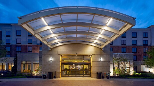 A hotel entrance with a covered entrance, a number '1307' above the doors, and a brick facade. - Hilton Garden Inn Akron (Akron)
