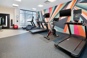 A gym with treadmills, stationary bikes, and exercise balls.