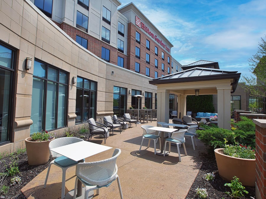 A hotel courtyard with outdoor seating, large windows, and a brick facade.