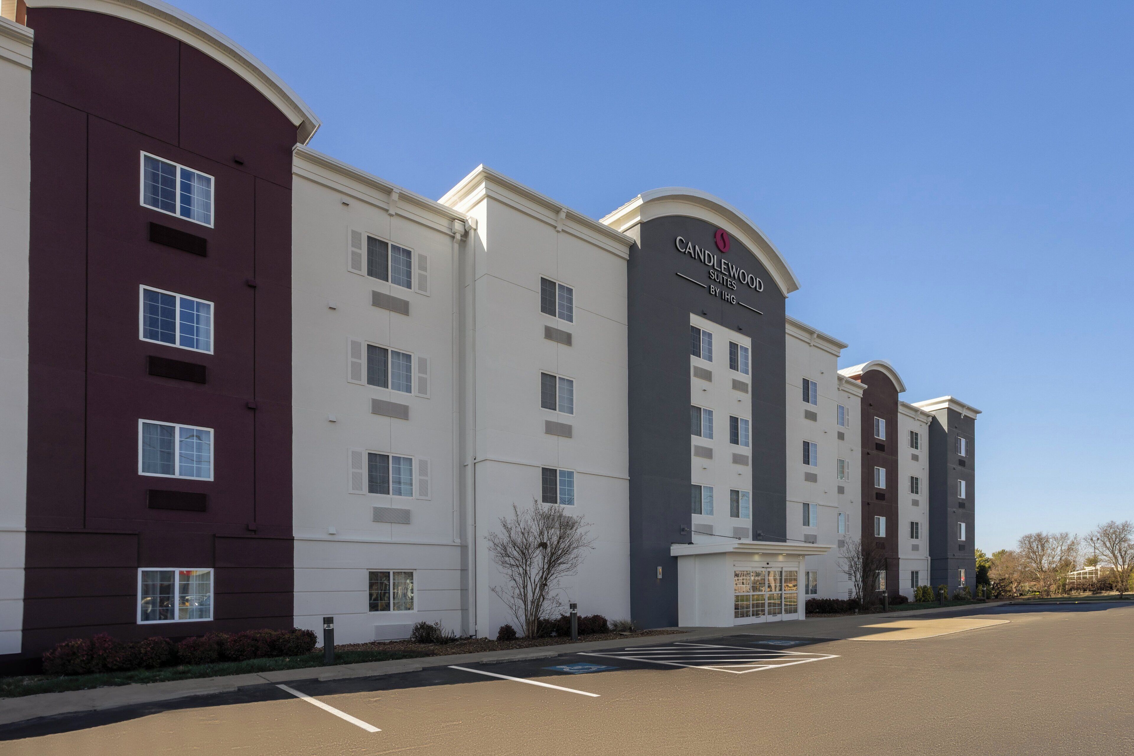 A multi-story hotel with a modern design, featuring a prominent entrance and a parking lot in front.