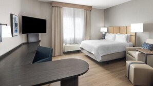 A modern hotel room with a bed, bedside tables, a desk, a flat-screen TV, and a large window with curtains. - Candlewood Suites Fort Campbell - Oak Grove by IHG (Oak Grove)
