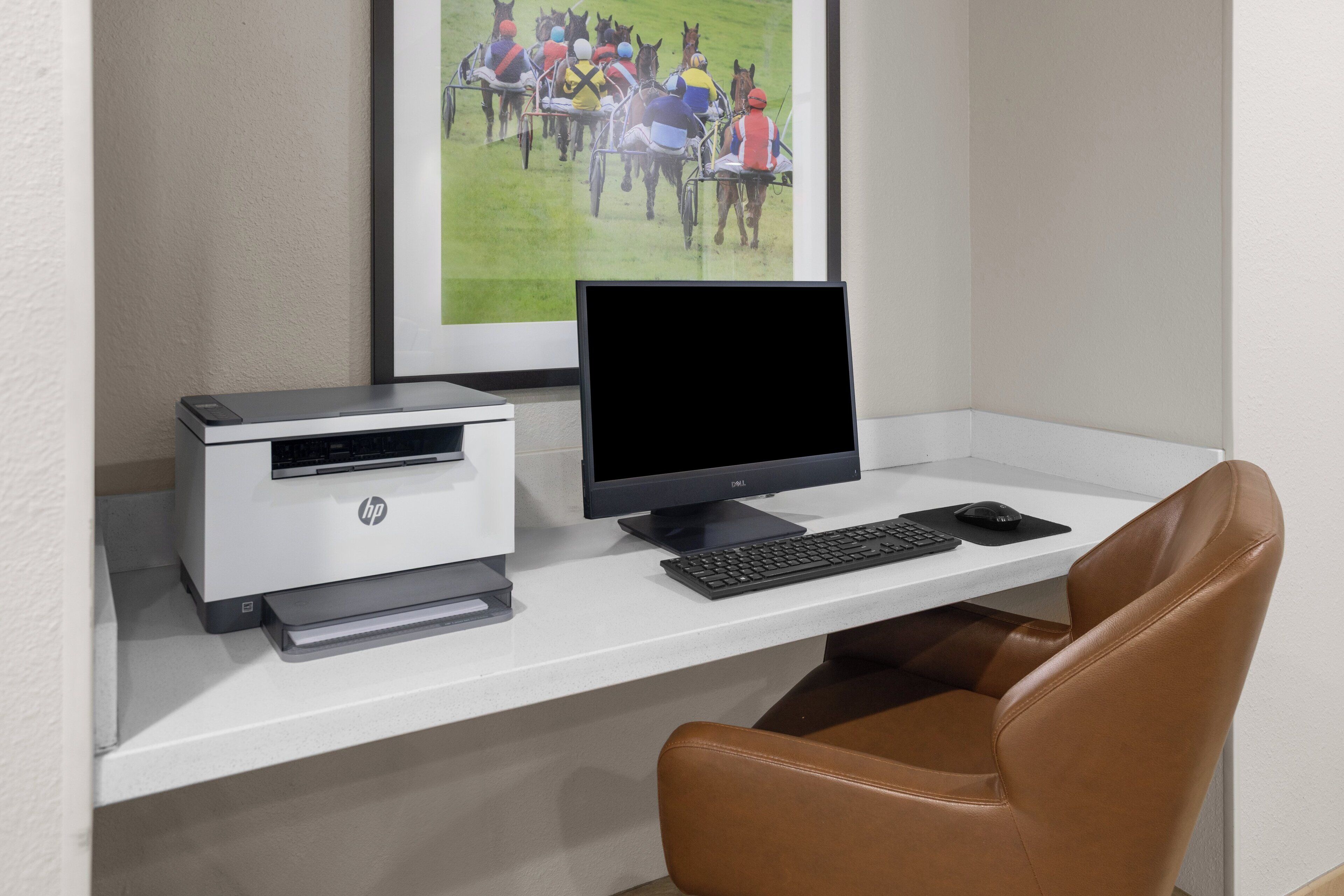 Een werkplek met een printer, monitor, toetsenbord en stoel.
