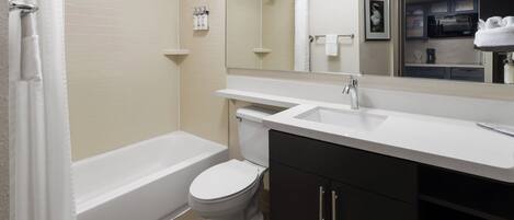 A modern bathroom with a bathtub, toilet, and vanity.