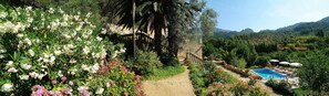 A garden with a pool, a pathway, and a view of the surrounding hills. - Finca sa Màniga (Bunyola)
