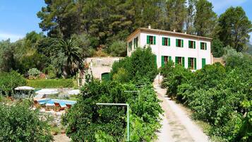Una villa con jardín, piscina y un camino que lleva a la casa.