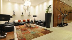 A modern living room with a sectional sofa, a coffee table, and a large rug. - Hotel Ekuikui I (Huambo)