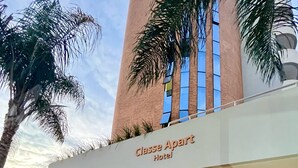 Vue extérieure de l’hôtel Classe Apart, avec son espace piscine, son escalier et ses palmiers.