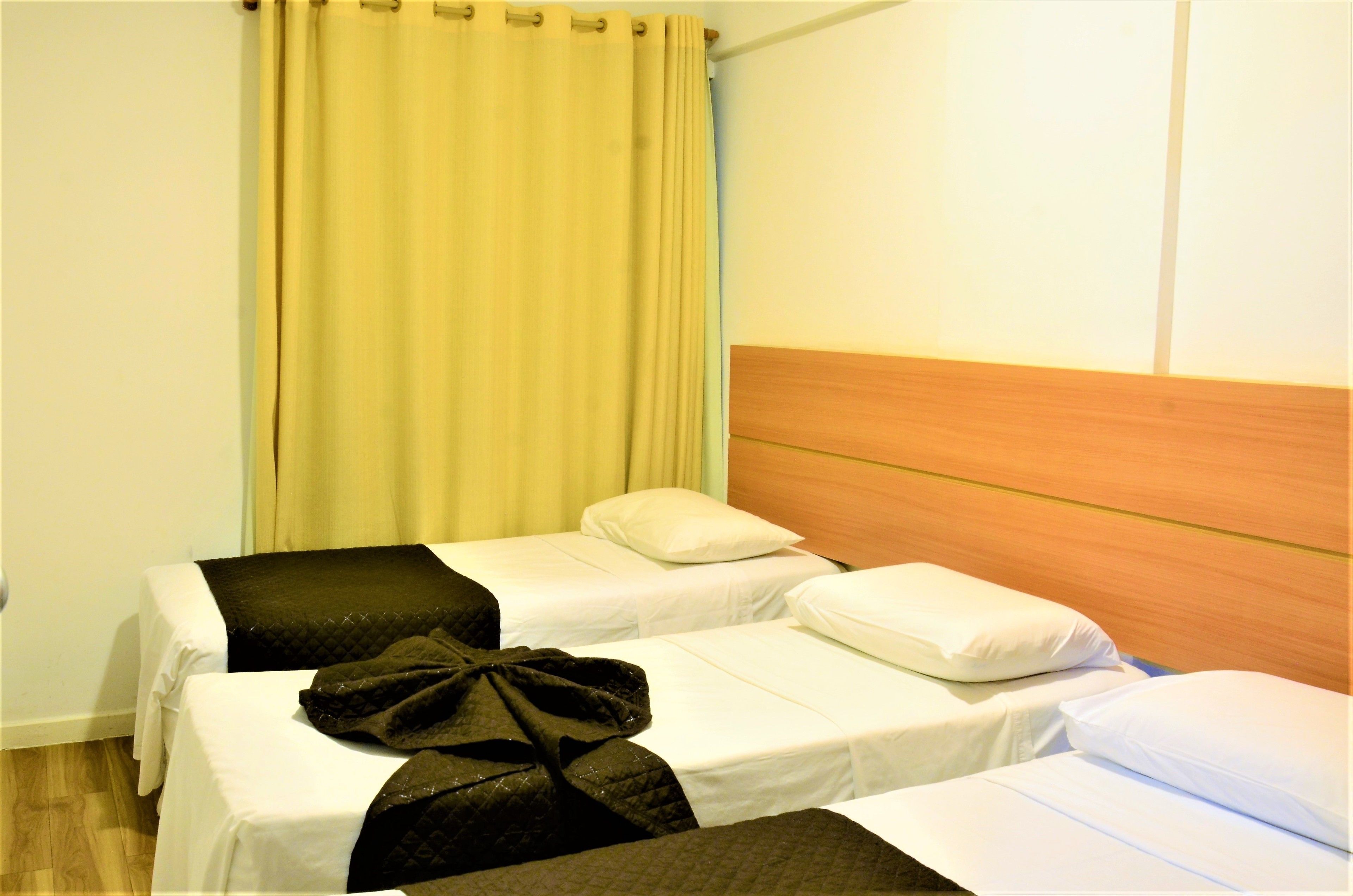 A hotel room with two single beds, a wooden headboard, and a yellow curtain.