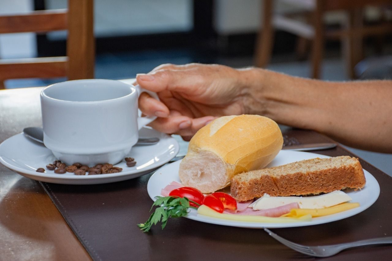 A meal consisting of a sandwich, a cup, and a plate with various food items.
