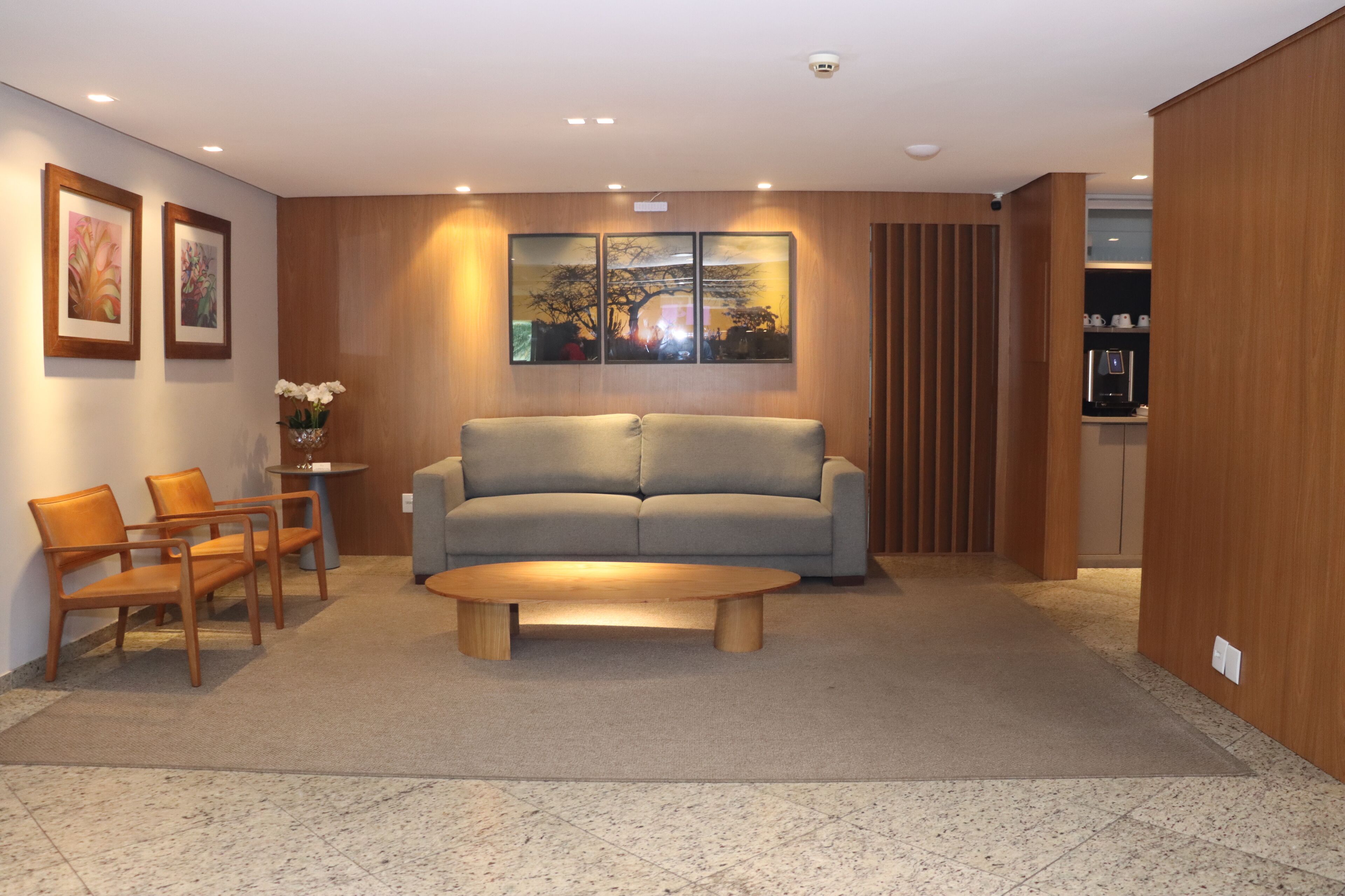 A modern living room with a sofa, chairs, a coffee table, and artwork on the wall.