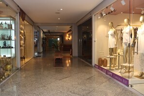 Un pasillo con un escaparate de vidrio que muestra maniquíes con vestidos blancos, un banco y un extintor.