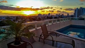 Un área de piscina en la azotea con mobiliario de mimbre y una planta en maceta.