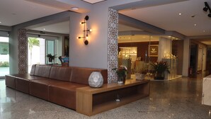 Un vestíbulo moderno con un sofá de cuero marrón, una mesa consola de madera y jarrones decorativos.