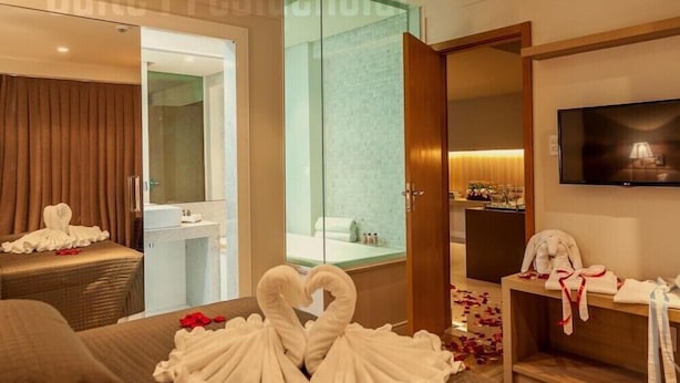 Una habitación de hotel con cama, baño, televisor y un separador de vidrio.