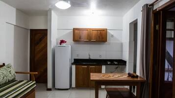 Uma cozinha compacta com armários de madeira, uma geladeira e uma mesa de jantar com cadeiras.